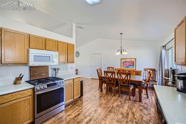 kitchen with an inviting chandelier, wood-type flooring, vaulted ceiling, pendant lighting, and stainless steel appliances