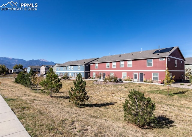 back of property featuring a mountain view and a lawn