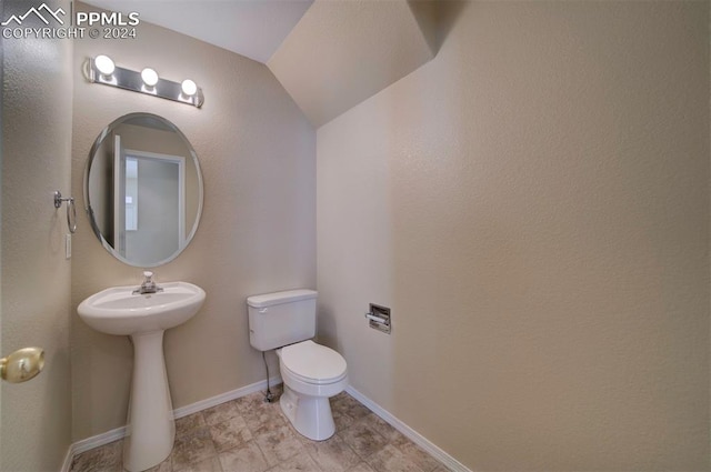 bathroom with sink, toilet, and lofted ceiling