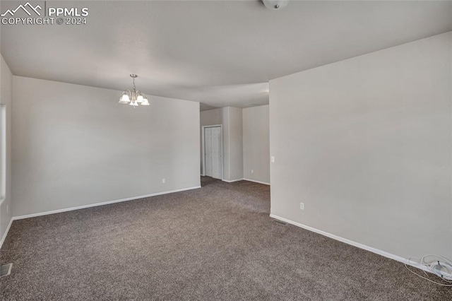 unfurnished room with a chandelier and dark carpet