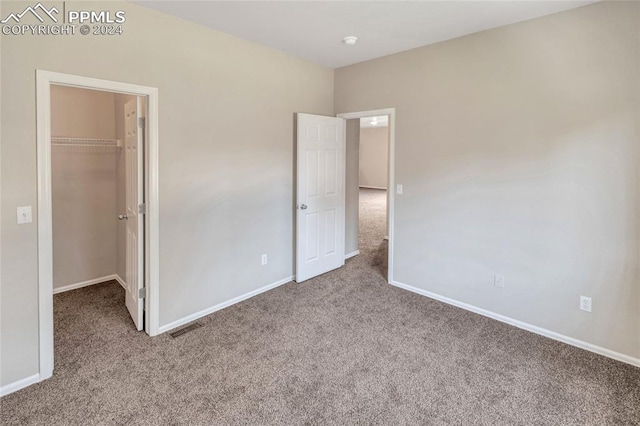 unfurnished bedroom with light carpet, a walk in closet, and a closet