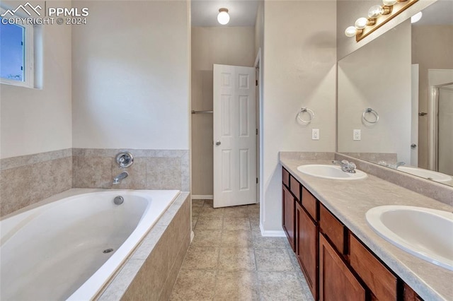 bathroom featuring a relaxing tiled tub and vanity