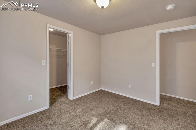 unfurnished bedroom featuring carpet floors, a walk in closet, and a closet