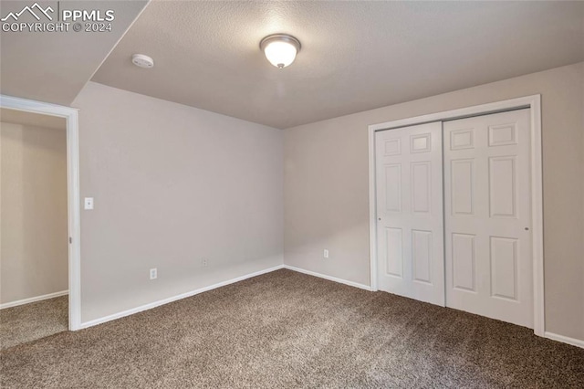 unfurnished bedroom featuring carpet, a textured ceiling, and a closet