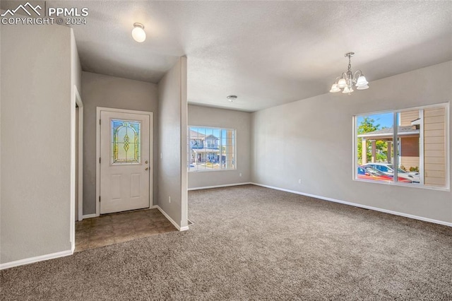 carpeted foyer with a textured ceiling and a notable chandelier