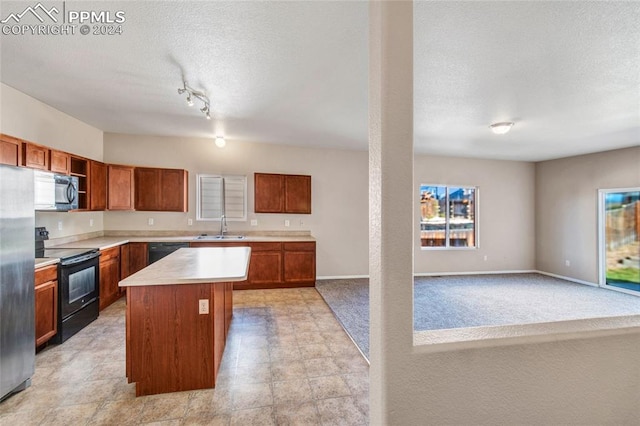 kitchen with sink, black appliances, a textured ceiling, rail lighting, and a center island