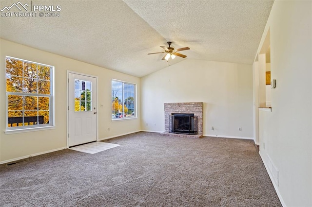 unfurnished living room with lofted ceiling, carpet, a brick fireplace, and ceiling fan