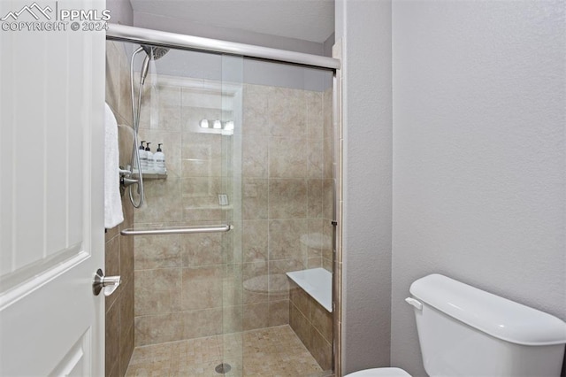 bathroom with toilet and a shower with shower door