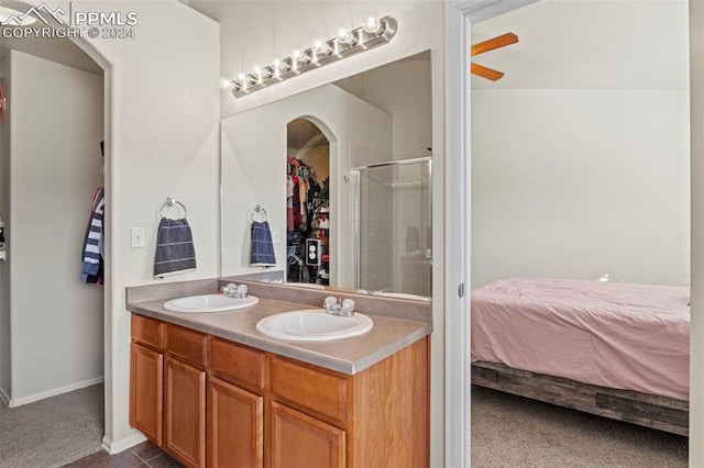 bathroom with vanity, a shower with shower door, and ceiling fan