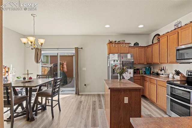 kitchen with a kitchen island, stainless steel appliances, decorative light fixtures, an inviting chandelier, and light hardwood / wood-style floors