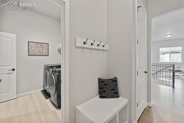 laundry area with light hardwood / wood-style floors and washing machine and clothes dryer