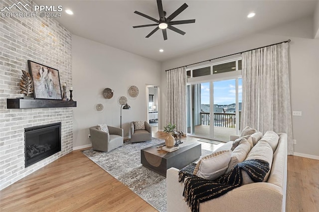 living room featuring hardwood / wood-style floors, ceiling fan, and a brick fireplace