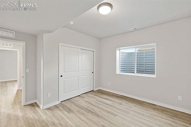 unfurnished bedroom with light hardwood / wood-style floors and a closet