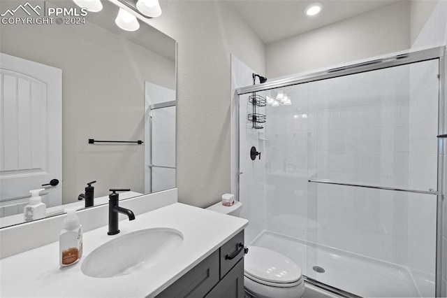 bathroom featuring a shower with shower door, vanity, and toilet