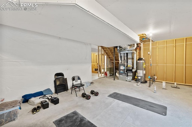 exercise room featuring heating unit, gas water heater, and concrete floors