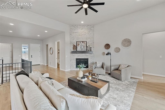 living room featuring a fireplace, light hardwood / wood-style floors, and ceiling fan