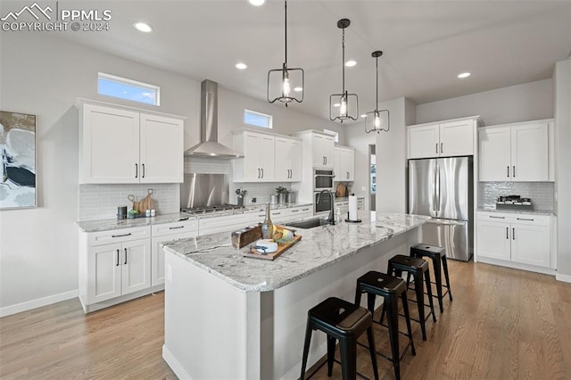 kitchen featuring white cabinets, stainless steel appliances, sink, and wall chimney range hood