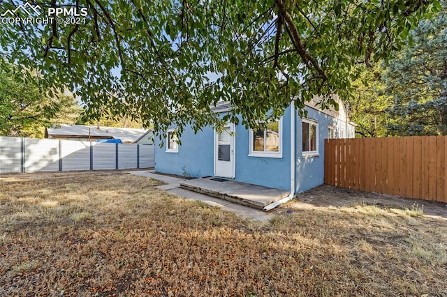 back of property with a patio area and a lawn