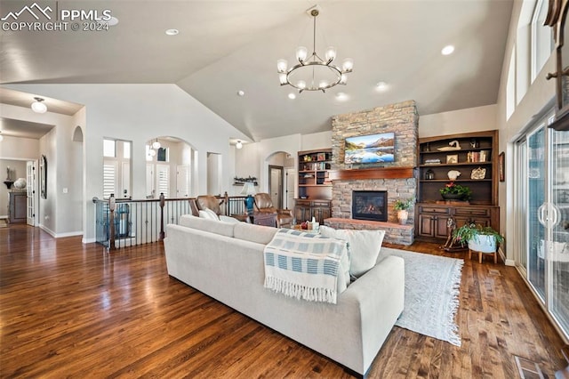 living room with dark hardwood / wood-style flooring, built in shelves, high vaulted ceiling, a fireplace, and a chandelier