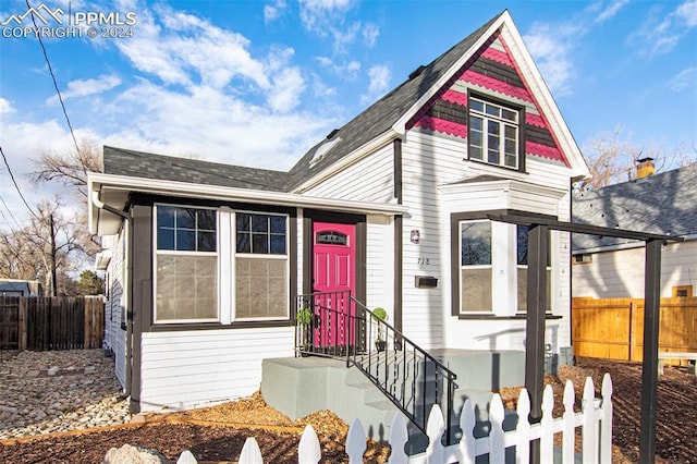 victorian-style house with a shingled roof and fence