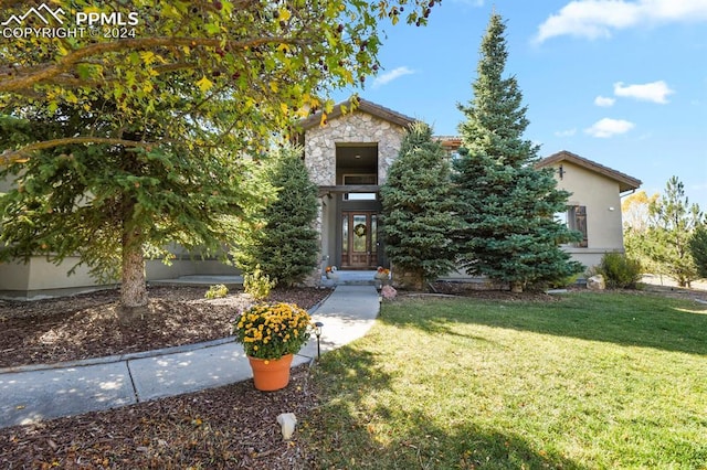obstructed view of property featuring stucco siding, a front lawn, and stone siding