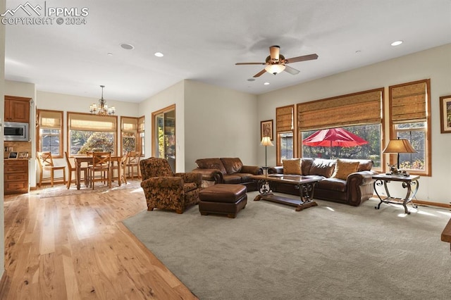 living room with baseboards, recessed lighting, light wood-style floors, and ceiling fan with notable chandelier