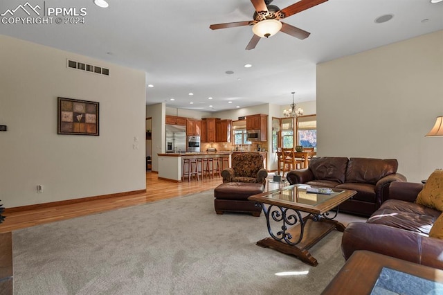 living area featuring baseboards, visible vents, recessed lighting, light colored carpet, and ceiling fan with notable chandelier