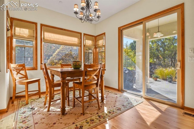 dining space with baseboards, wood finished floors, visible vents, and a chandelier