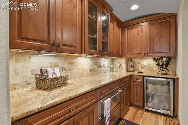 kitchen with wine cooler, decorative backsplash, light stone countertops, and light wood-type flooring