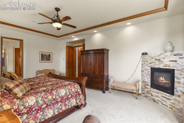 carpeted bedroom featuring ceiling fan and a stone fireplace