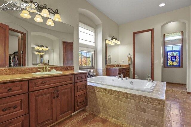full bathroom with toilet, a garden tub, two vanities, and a sink
