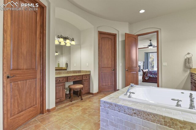 bathroom featuring vanity, tile patterned flooring, tiled bath, and ceiling fan