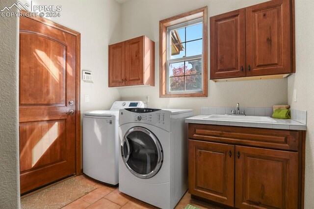 laundry area with cabinets, sink, washer and clothes dryer, and light tile patterned floors