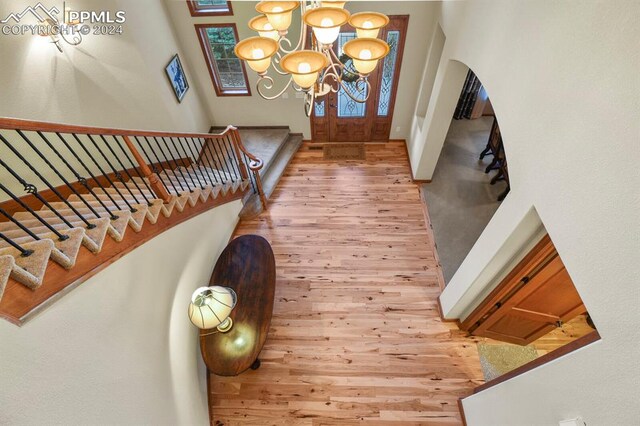 entryway with a high ceiling, wood-type flooring, and an inviting chandelier