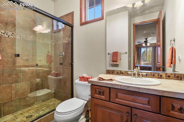 bathroom featuring vanity, toilet, a shower with door, and ceiling fan