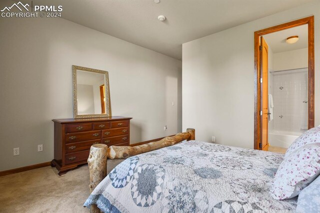 bedroom with ensuite bathroom and light colored carpet