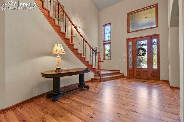 entryway featuring stairway, a high ceiling, wood finished floors, and baseboards