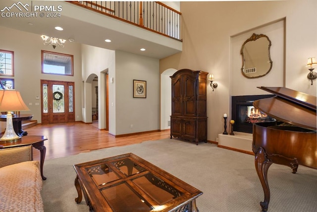 living area with light colored carpet, arched walkways, a towering ceiling, and a wealth of natural light