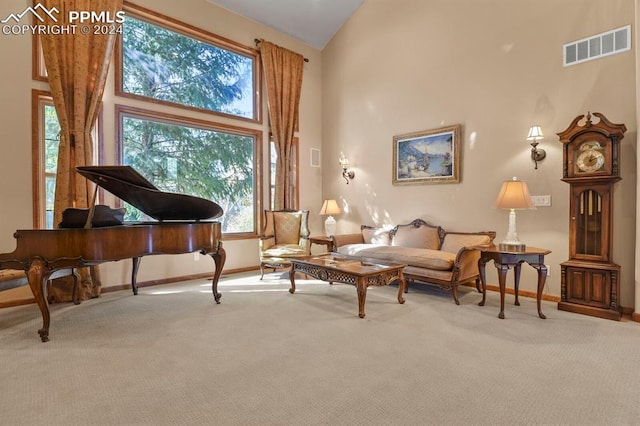 sitting room with baseboards, visible vents, carpet floors, and high vaulted ceiling