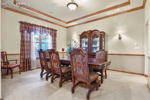 dining space featuring ornamental molding and light colored carpet