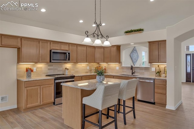 kitchen with sink, a kitchen island, plenty of natural light, stainless steel appliances, and light hardwood / wood-style flooring