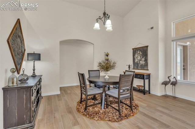 dining room featuring light hardwood / wood-style floors, high vaulted ceiling, and a chandelier