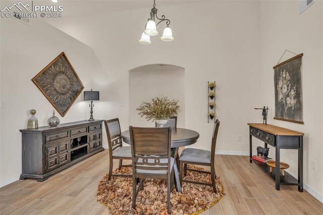 dining area with vaulted ceiling, a notable chandelier, and light wood-type flooring