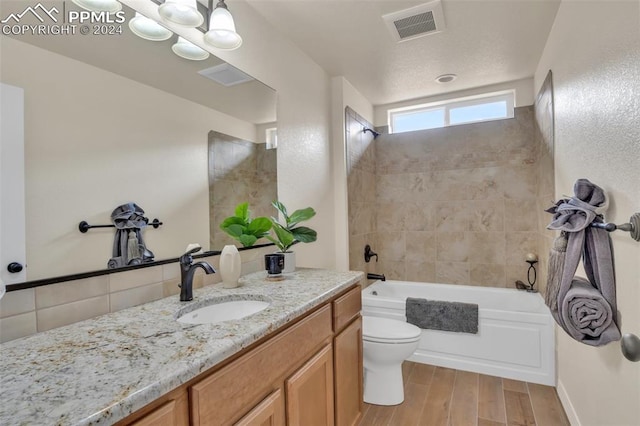 full bathroom with vanity, toilet, wood-type flooring, and tiled shower / bath