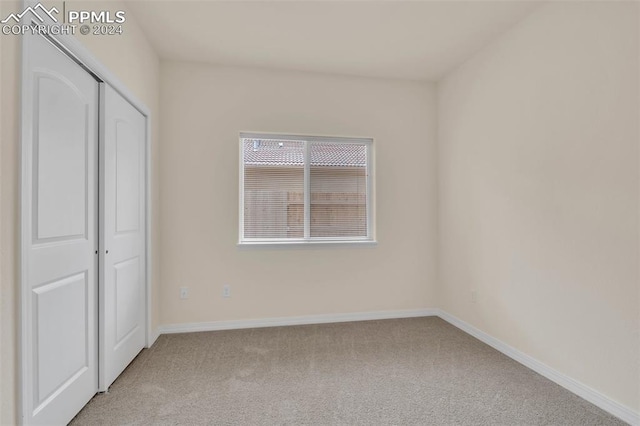 unfurnished bedroom with light carpet and a closet