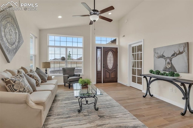 living room featuring light hardwood / wood-style flooring, high vaulted ceiling, and ceiling fan