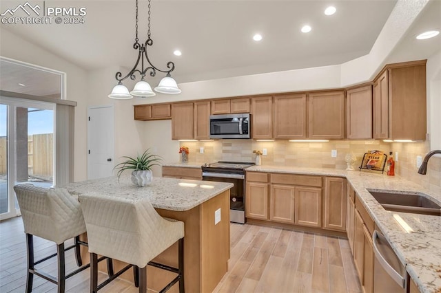 kitchen featuring sink, light wood-type flooring, backsplash, stainless steel appliances, and pendant lighting