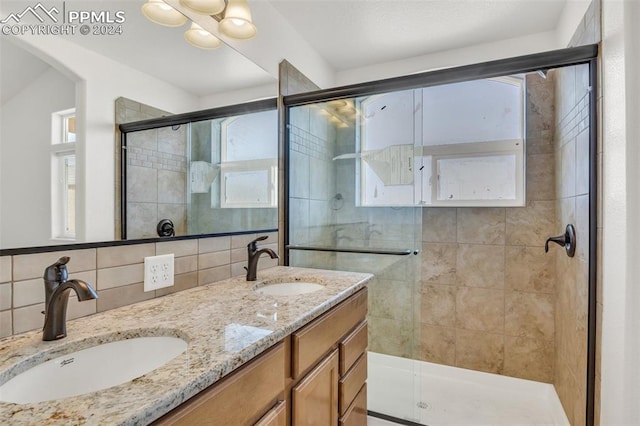 bathroom with tile walls, vanity, a shower with shower door, and tasteful backsplash