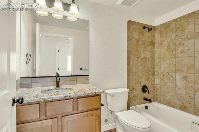 full bathroom featuring vanity, tiled shower / bath combo, and toilet