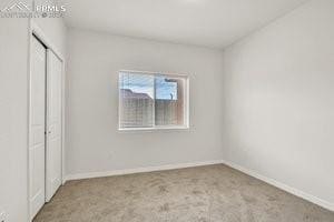 unfurnished bedroom featuring light carpet and a closet